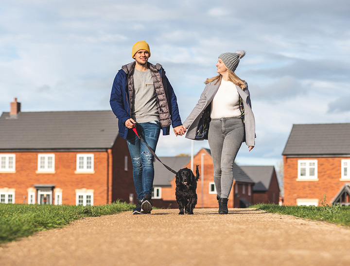 Image of young couple walking their dog in a new neighbourhood